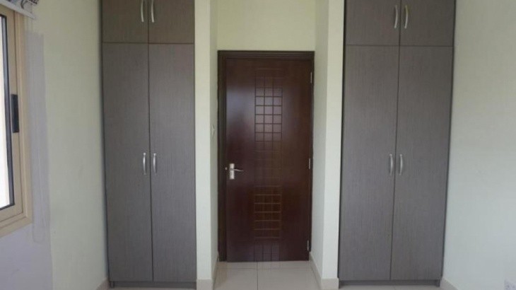 Apartment bedroom entrance door with the two cupboard spaces for clothes, double glazed window and ceramic floor