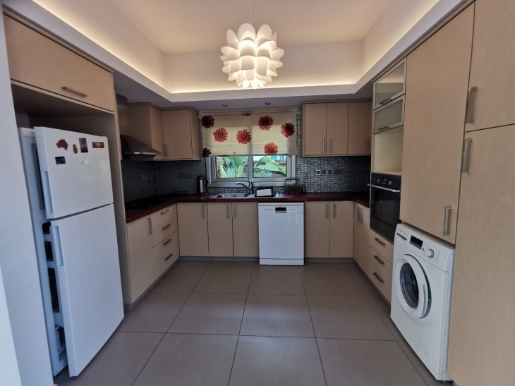 The kitchen of the property, with a fridge, a washing machine, an oven, an extractor fan, and a sink