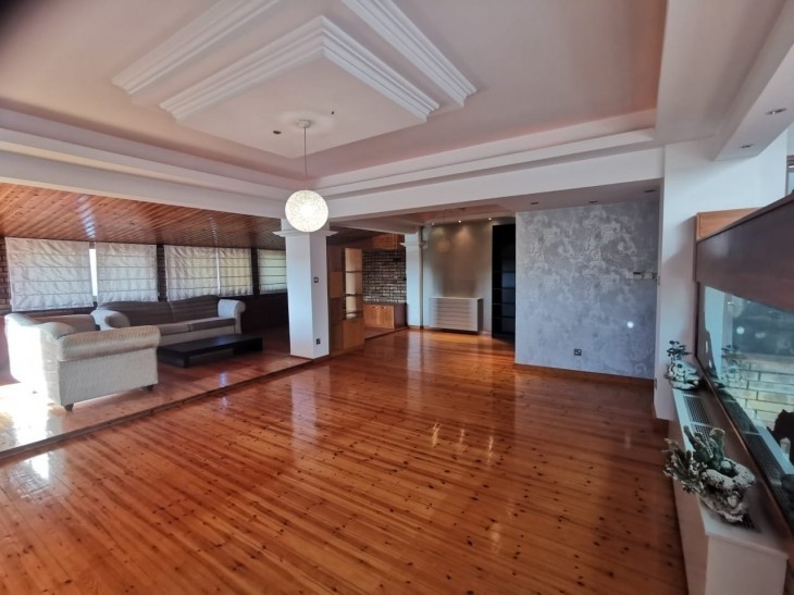 Picture of the spacious living room area, being partly furnished and having laminate parquet flooring.