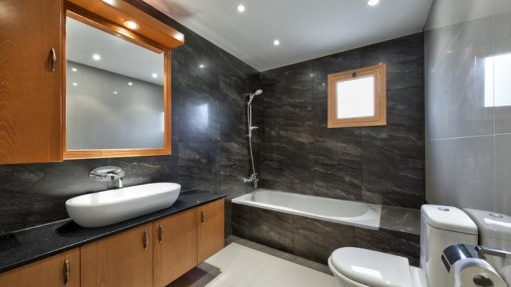 the space of the family bathroom, with a bathtub, a toilet, a sink, a cupboard with a fitted mirror, and wooden counters