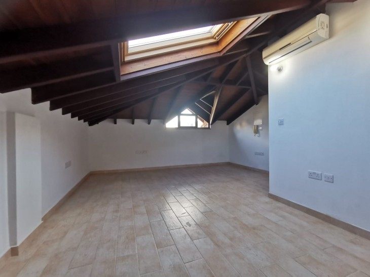 A bedroom of the property, located in the attic, with wooden ceiling and an attic window