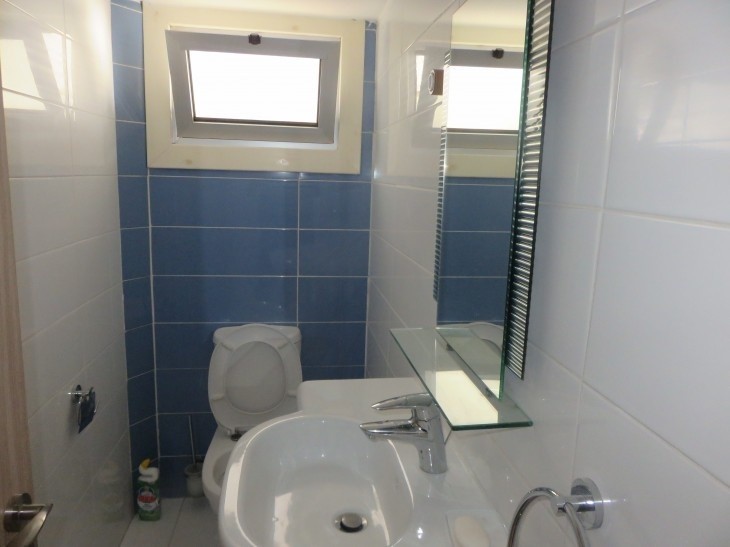Picture of the toilet room with a sink, toilet unit, and a window.