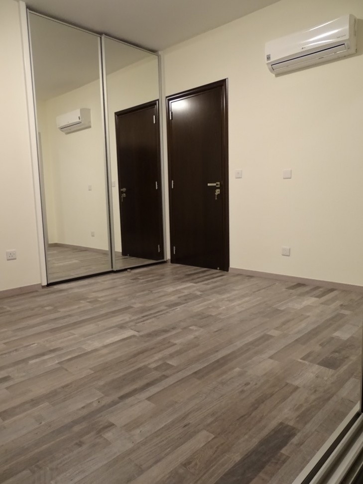 Picture of the third of the bedrooms, equipped with laminate parquet flooring, a mirror-cupboard, and an air-conditioning unit.