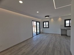Large open plan living room, dining, and kitchen area with parquet flooring.