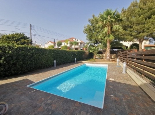 the area of the swimming pool that is uncovered and is surrounded by trees, plants and wooden fence