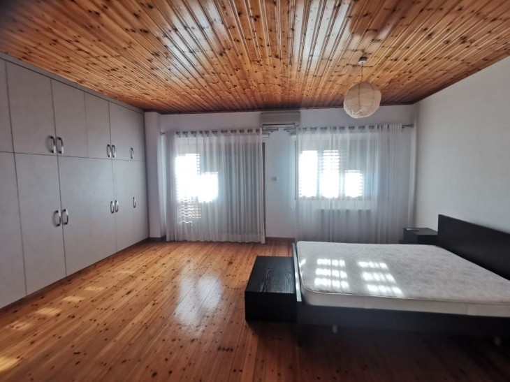 Picture of the main bedroom of the upper-level house, having laminate parquet flooring, an air-conditioning unit, and large cupboard space.