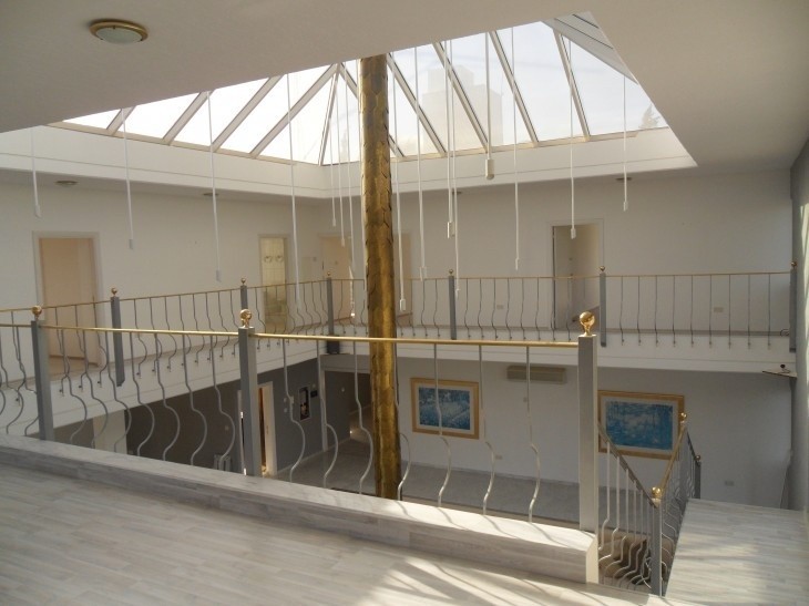 the space of the living room from the second floor of the house, with the iron fence, the bedroom doors, and the glass ceiling