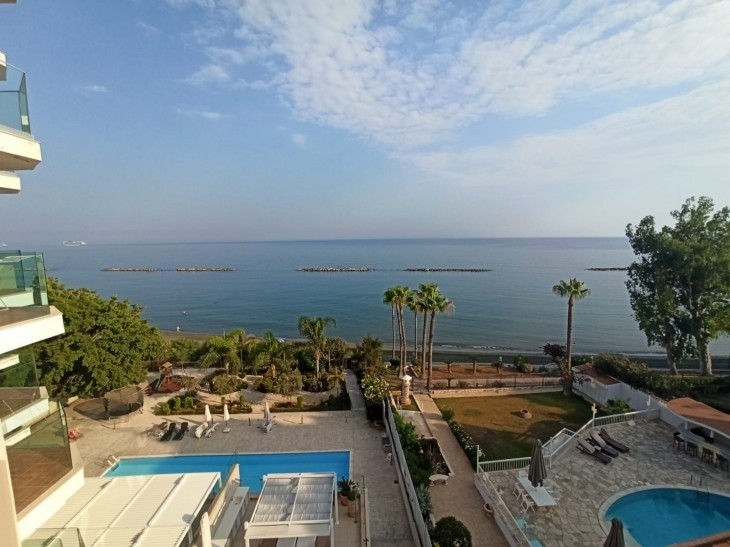 the view of the balcony of the apartment that shows the sea and the two swimming pools of the building