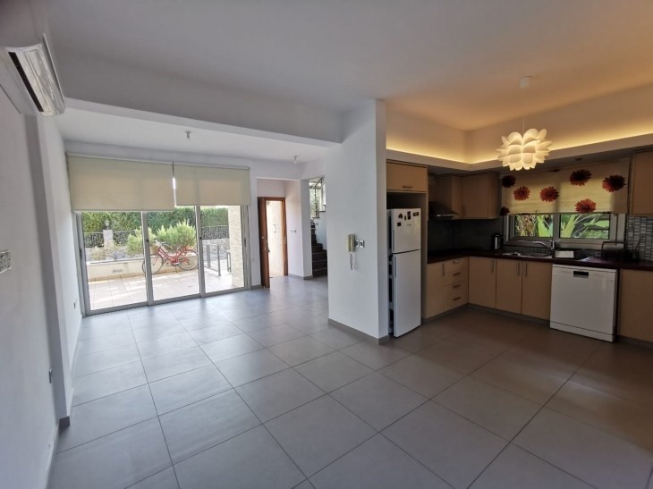 The open plan kitchen and living room areas with electrical appliances and windows to the veranda