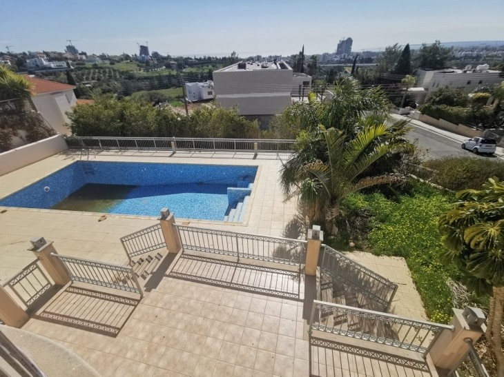 The area outside shows us the multiple staircases that lead to the main entrance of this house, the rectangular pool, and the green area around.