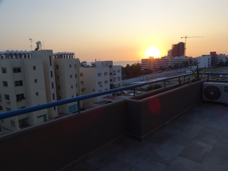 Picture of the covered balcony of the apartment offering a brilliant sunset view.